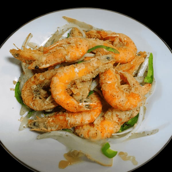 Crispy fried shrimp with sliced onions and green peppers on a white plate.