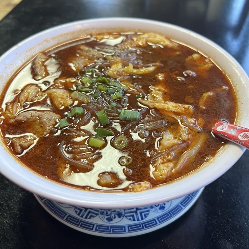 A bowl of hot and sour soup with noodles, meat, and green onions from Bao Bao Chinese Bistro.