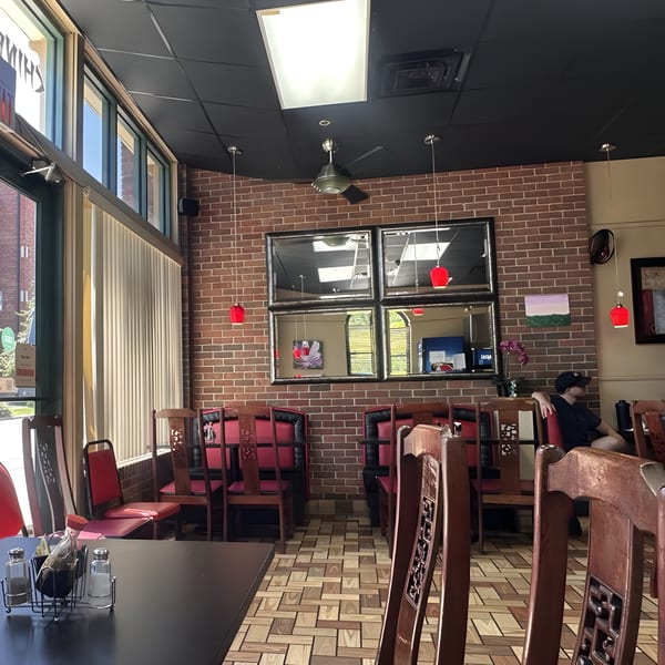 Interior of Bao Bao Chinese Bistro with red chairs, brick walls, and a customer seated.
