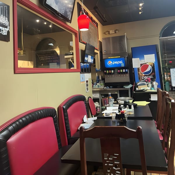 Interior of Bao Bao Chinese Bistro with red booths, dark tables, and a Pepsi soda fountain.